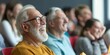 © gunzexx png and bg - A group of people sitting in an auditorium, attentively watching a stage event or presentation, showcasing engagement and collective focus in a professional setting.