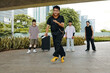 © DragonImages - Group of friends enjoying dancing together in an urban park with skateboard and luggage in background. Skyscrapers and trees in scene adding to urban atmosphere