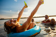 © Zoran Zeremski - Group of young friends having fun and enjoying a summer day swimming with rubber tube and drinking beer at the lake.