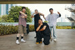 © DragonImages - Group of young friends striking various poses outdoors under pavilion on sunny day. Building and plants visible in background