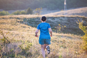 Wall Mural - Woman running free on the hill on golden sunset.