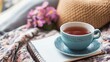 © BozStock - A cup of tea on a blanket with a notebook and flowers.