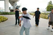 © DragonImages - Group of young men engaging in street dance practice in urban environment near large structure with plants and bench. Movement and coordination emphasized in choreography