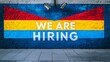 © kaiserseeing - 'We Are Hiring' mural painted in bold red, yellow, and blue colors on a brick wall, underlining dynamic recruitment opportunities.