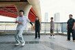© DragonImages - Group of young men showcasing street dance moves under bridge with urban background. Enthusiasts wearing casual clothing, creating vibrant, energetic atmosphere with surrounding architecture