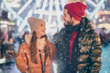 Wall Mural - Photo of loving couple talking under evening x-mas night illumination outside sky wear season coats scarf