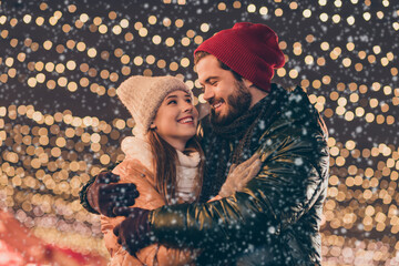 Sticker - Photo of loving couple embrace under x-mas evening outdoors lights wear season winter coats headwear