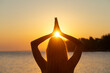 © Gajus - View from behind of a woman with long hair standing by the sea practicing mindfulness and gratitude at sunrise