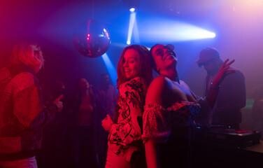 A group of male and female friends enjoying and having fun dance party together at disco nightclub