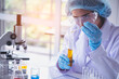 © aFotostock - Scientist woman holding chemical test yellow glass tube testing science laboratory. Lab technician holding gold fluid drop to glass tube Urine sample. Asian woman scientist working medical chemistry