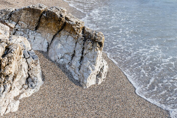 Wall Mural - White coastal rocks lay in wet sand on the beach