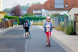 © Irina Schmidt - Little happy girl on way to school by pushing scooter. Elementary school child riding in the city, with big satchel. Kid with helmet. Safe route to school and movement for children concept.