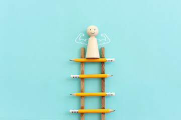 Poster - Concept image of a ladder made of pencils and wooden figure on top. Idea of education, success and achieving goals