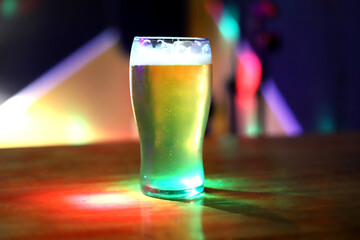 Glass of beer with foam on the table in a bar or pub. Background with copy space.