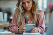 © PHAISITSAWAN - A female journalist with microphone, notebook, and phone in the office, closeup.