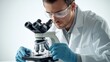 © Arpatsara - A focused scientist examines a sample under a microscope, showcasing the importance of research and discovery in the laboratory.