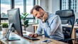 © Sirinporn - A tired office worker sits at a desk, rubbing their neck and shoulder, experiencing discomfort and strain from prolonged computer usage and poor posture.