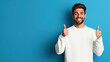 © OMD - Smiling man with beard and brown hair wearing white sweater showing thumbs up gesture against a blue background.