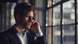 © VK Studio - A young man in a suit talks on the phone, framed by large windows that let in the soft, late afternoon sunlight.