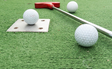 Fun vacation entertainment for summertime. Playing mini golf on green grass outdoors. Setting goals and winning lifestyle concept. Competition at golf course: two crossed sticks. Blank space for copy.