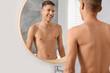 © New Africa - Handsome man looking at mirror in bathroom