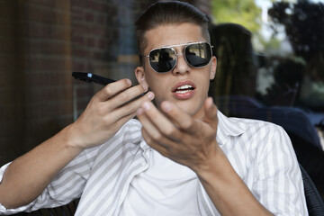 Poster - Young man recording voice message via smartphone in outdoor cafe