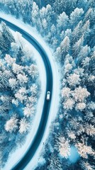 Aerial view of a lone car traversing a winding road through a snow-covered forest, creating a striking contrast between the blue asphalt and white winter landscape.