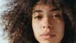 © VK Studio - A close-up portrait of a young woman with natural curls, soft lighting highlighting her facial features, evoking a sense of serene contemplation.