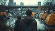 © Thanakan - Back view of father and son in urban homeless encampment with city buildings and tents in the background on a gloomy day.