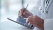 © sarana - Taking Notes on Tablet: Doctor's hands taking notes on a digital tablet, stylus in hand.
