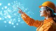 © weerasak - A woman in a hard hat and safety goggles points at a digital network, representing technological innovation and engineering progress.
