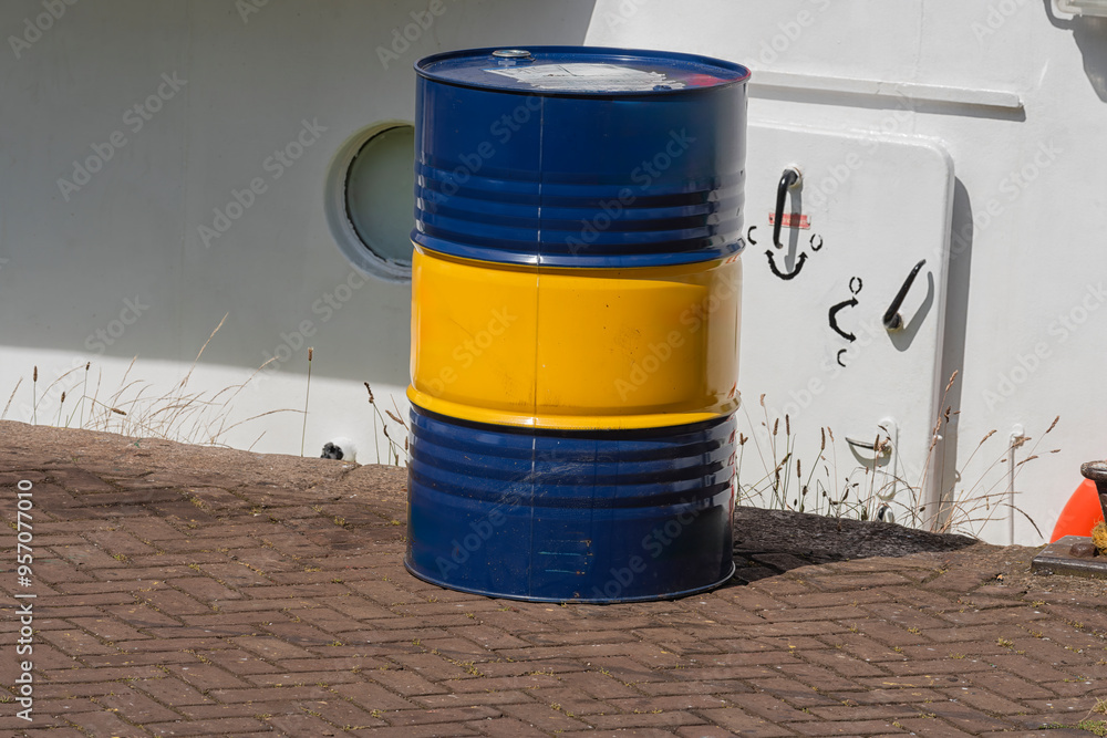 yellow blue oil barrel stands outside on the quay of the port