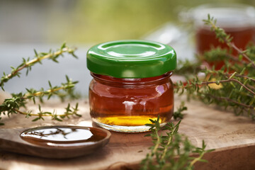 A jar of thyme syrup on a table outdoors