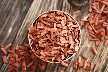 Wall Mural - Red sandalwood chips in a metal bowl on a wooden table, top view