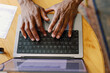 © Oleksii Syrotkin/Stocksy - Top view of partial black cafe owner hands typing on laptop at table