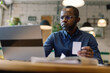 © Oleksii Syrotkin/Stocksy - Black male cafe owner holding bill and watching laptop at table