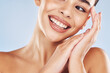 © Azee Jacobs/peopleimages.com - Woman, smile and closeup in studio for skincare, beauty and cosmetic with healthy skin, glow or texture. Model, mouth and hands on blue background for dermatology, aesthetic and facial transformation