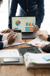 © Kritdanai - Strategic Business Analytics:  A team huddles over financial data, collaborating on a laptop with charts and graphs.