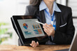 © Kritdanai - Data-Driven Insights: A businesswoman in a modern office setting presents key financial data on a tablet, showcasing a professional and analytical approach to business growth.