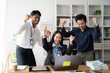 © Kritdanai - Office Triumph: A jubilant team celebrates success, their energy palpable as they gather around a laptop in a modern office.