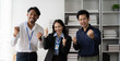 © Kritdanai - Office Triumph: A trio of ecstatic Asian professionals celebrate success in their modern office, fists pumping with joy.