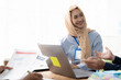 © Kritdanai - Confident Collaboration: A young woman wearing a hijab confidently presents her ideas during a business meeting, fostering a productive and inclusive work environment.