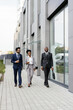 © Oleksii Syrotkin/Stocksy - Businessman walking with business associates past corporate building