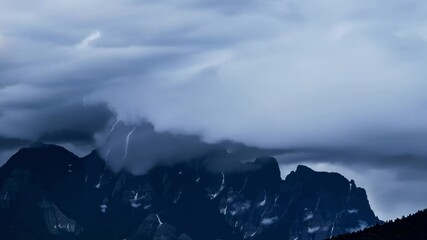 Wall Mural - Dramatic storm clouds gather over majestic mountain peaks, casting shadows in a fantasy like atmosphere. The rocky terrain adds to the breathtaking scenery