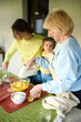 © Iuliia Versta/Stocksy - Granny with her daughter and granddaughter cooking  in the kitchen