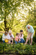 © Iuliia Versta/Stocksy - a grandparents with daughter and grandchildren working in the garden
