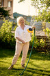 © Iuliia Versta/Stocksy - Senior woman watered a tree in the garden