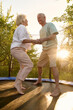 © Iuliia Versta/Stocksy - a senior couple jumps on a trampoline