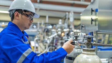 Asian engineer working at Operating hall,Thailand people wear helmet  work,He worked with diligence and patience,she checked the valve regulator at the hydrogen tank.