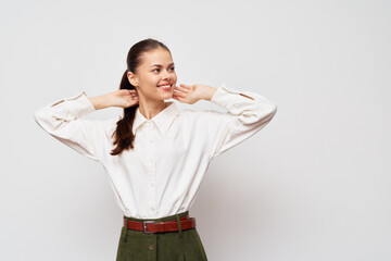 Happy young woman in a white shirt and green pants smiling on a light background, expressing joy and satisfaction, ideal for lifestyle, fashion, and portrait themes